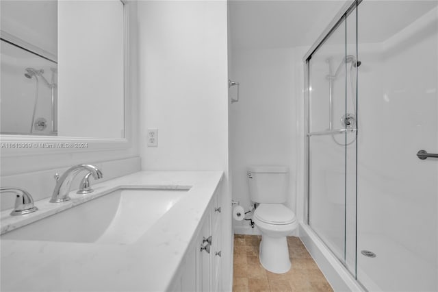 bathroom featuring a shower with shower door, toilet, and vanity