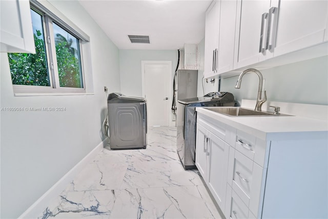 clothes washing area with washer / clothes dryer, cabinets, and sink