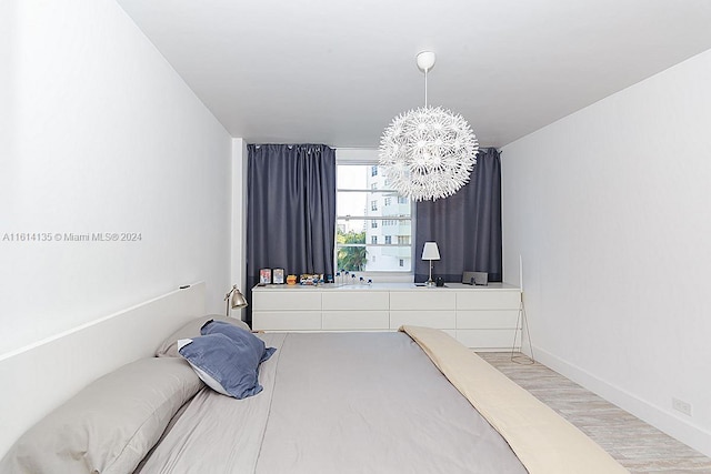 3 Island Ave Unit 04J, Miami Beach, FL 33139 - bedroom featuring a chandelier, light wood-style flooring, and baseboards