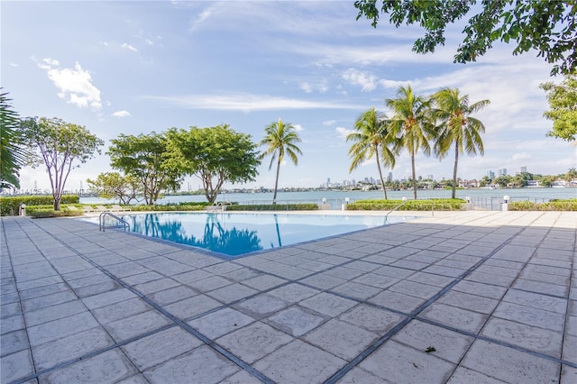 view of pool featuring a water view and a patio