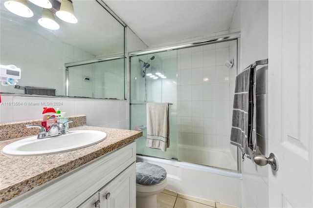 full bathroom featuring decorative backsplash, combined bath / shower with glass door, vanity, tile patterned flooring, and toilet