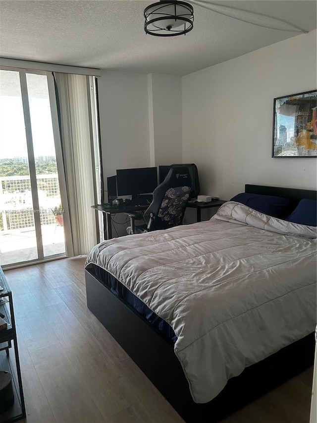 bedroom with hardwood / wood-style floors, a textured ceiling, and access to outside