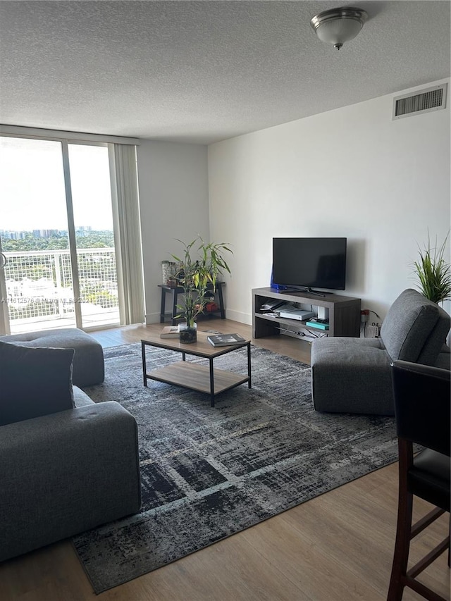 living room featuring a textured ceiling, hardwood / wood-style floors, and expansive windows