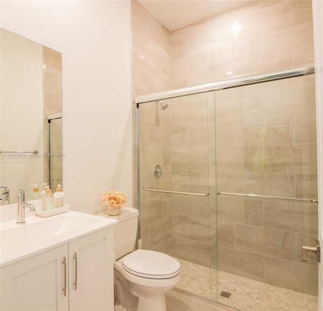 bathroom featuring vanity, toilet, and a shower with shower door