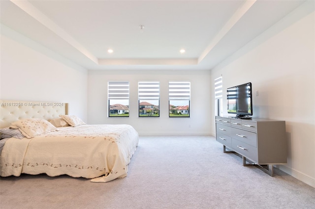 bedroom with light carpet and a tray ceiling