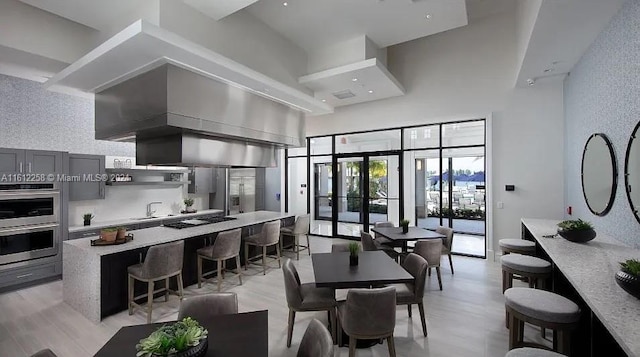 dining space featuring french doors, a towering ceiling, light wood-type flooring, and sink