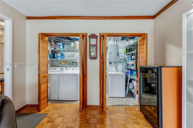 clothes washing area featuring electric panel, light parquet floors, washer and dryer, and a textured ceiling