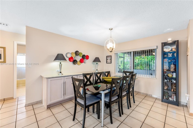 tiled dining room with a textured ceiling and a notable chandelier