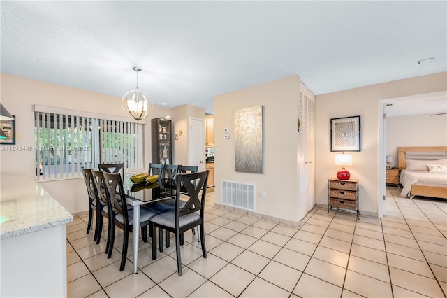 tiled dining area featuring a notable chandelier and a textured ceiling