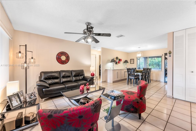 living room with ceiling fan, light tile patterned floors, and a textured ceiling