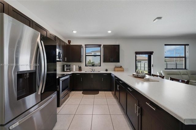 kitchen featuring plenty of natural light, sink, stainless steel appliances, and light tile patterned floors