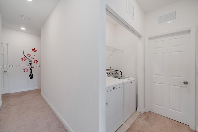 laundry room with washer and dryer and light colored carpet