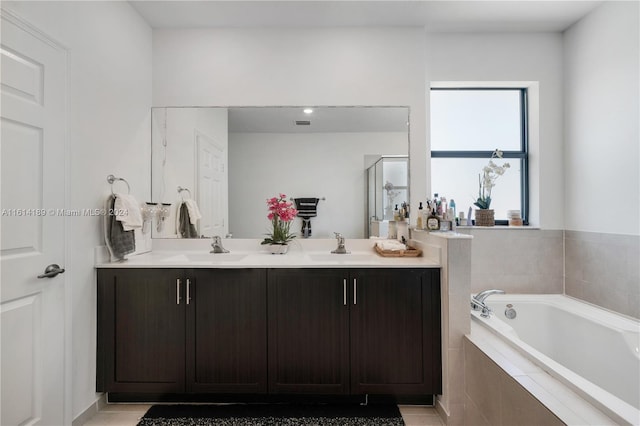 bathroom with dual vanity, tile patterned floors, and a relaxing tiled tub