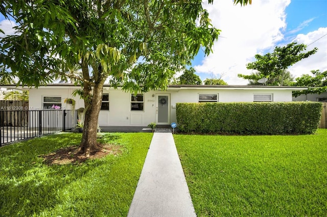 ranch-style home with a front lawn, fence, and stucco siding