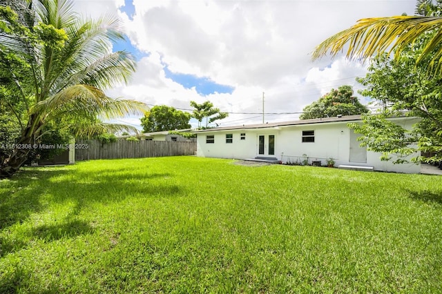 back of property featuring a yard, french doors, fence, and stucco siding