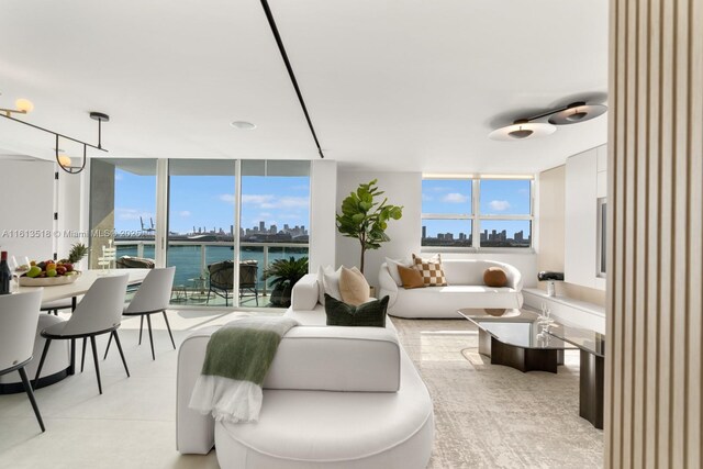 living room with light tile flooring, a water view, and expansive windows