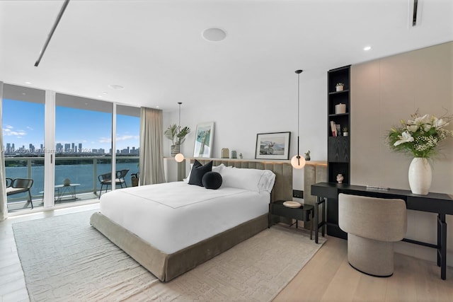 bedroom with expansive windows, access to exterior, and light wood-type flooring