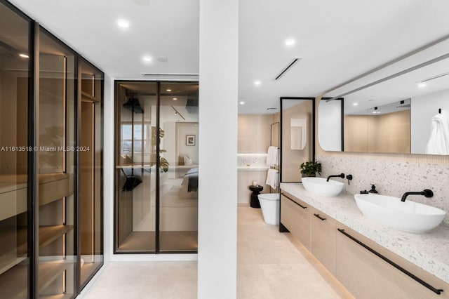 bathroom featuring vanity, a shower with shower door, backsplash, and toilet