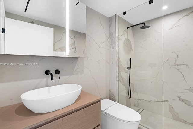 bathroom with vanity, toilet, tile walls, and a tile shower