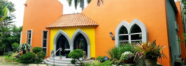 rear view of house featuring stucco siding and a tiled roof