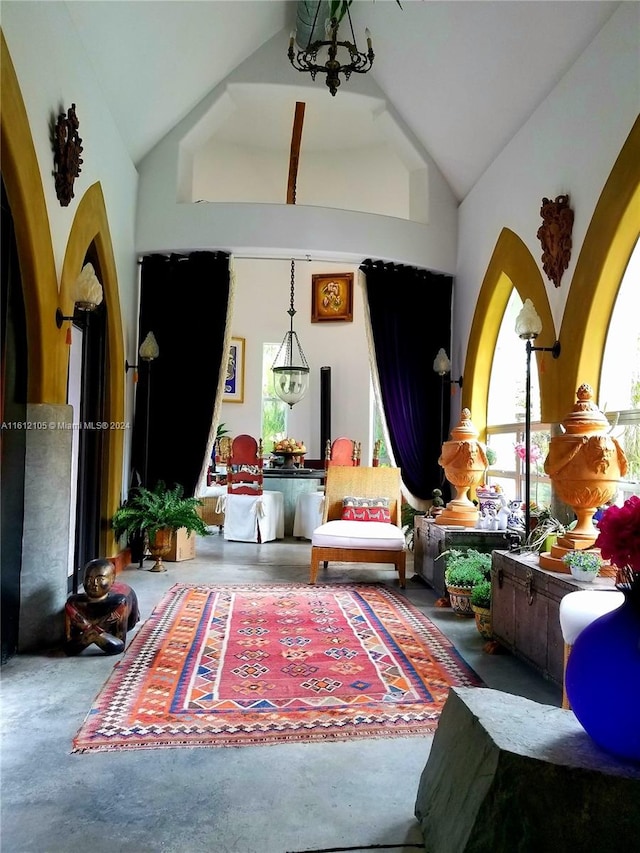 sitting room with vaulted ceiling, concrete flooring, and an inviting chandelier