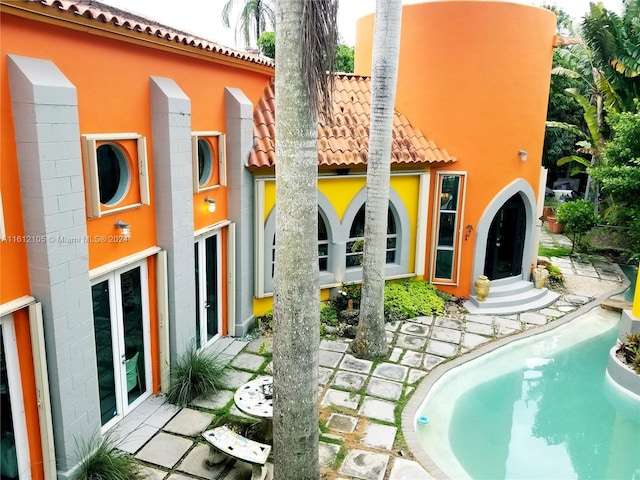 back of house featuring french doors, a tile roof, and stucco siding