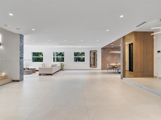 unfurnished living room featuring light tile patterned floors and wooden walls