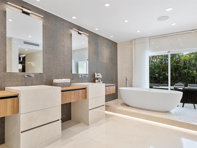 bathroom featuring tile patterned floors, a tub to relax in, vanity, and tile walls