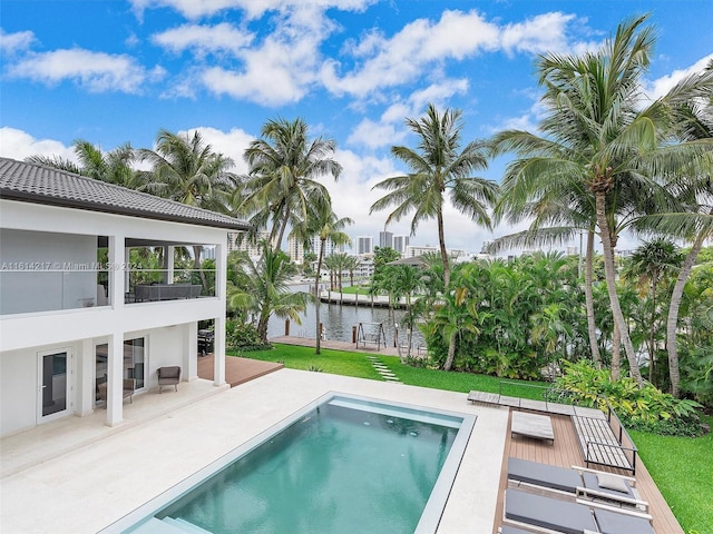 view of pool with a yard, a patio area, and a water view