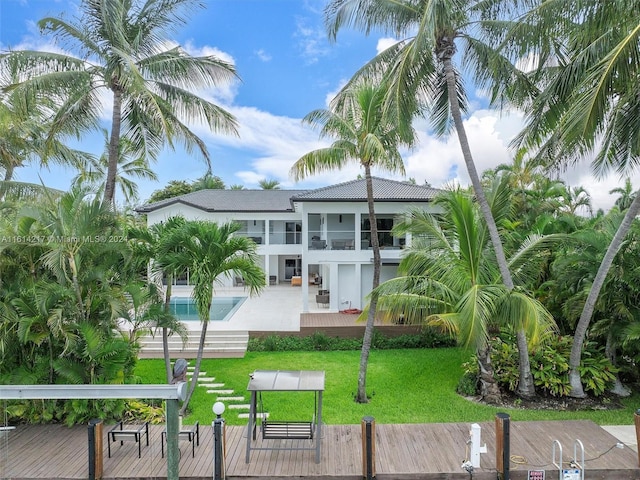 back of property with a yard, a balcony, and a swimming pool side deck