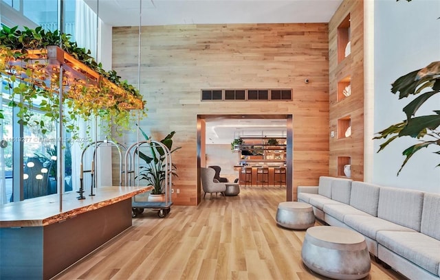 interior space featuring visible vents, wooden walls, a high ceiling, and wood finished floors