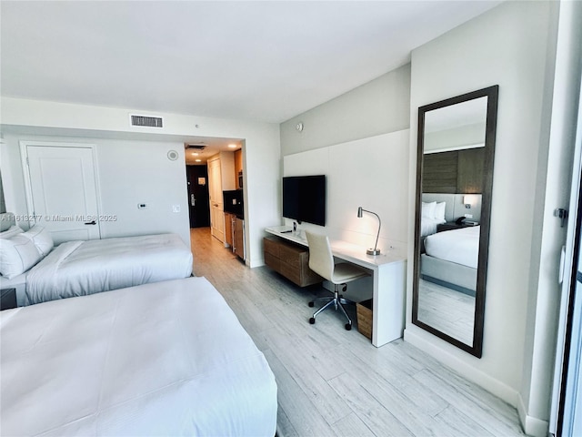 bedroom with visible vents, built in desk, and light wood-type flooring