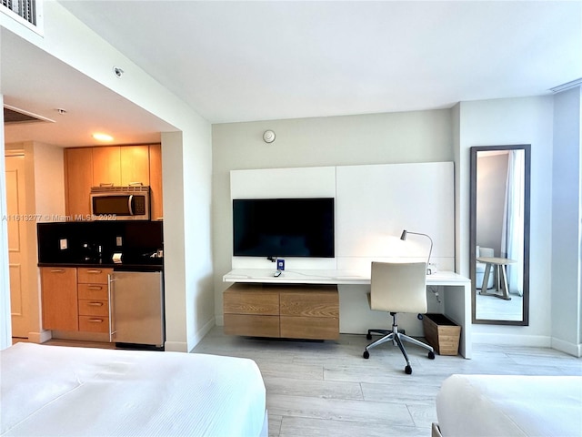 bedroom with visible vents, baseboards, light wood-style floors, and refrigerator