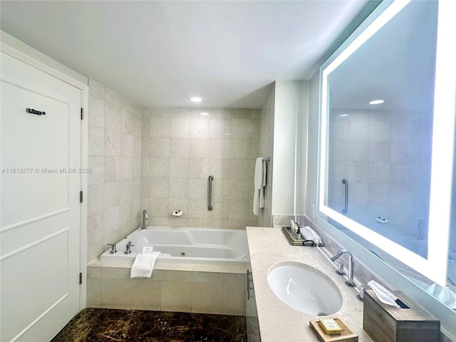 bathroom with recessed lighting, a tub with jets, and vanity