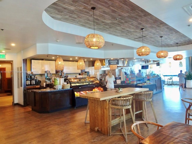 kitchen featuring a kitchen bar, pendant lighting, dark wood-style floors, and a kitchen island