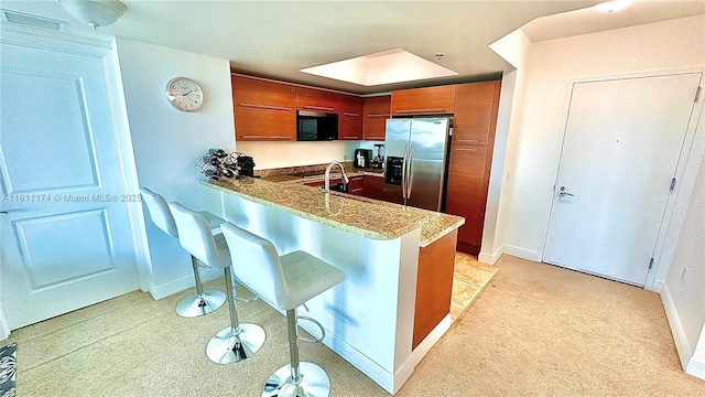 kitchen with stainless steel fridge with ice dispenser, kitchen peninsula, a breakfast bar, and sink