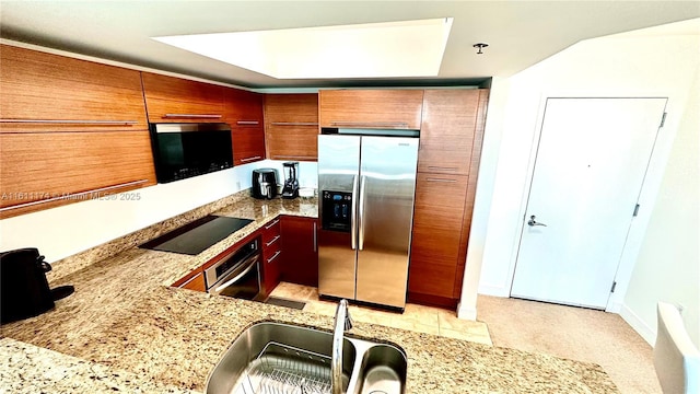 kitchen featuring light stone countertops, light tile patterned floors, appliances with stainless steel finishes, and sink