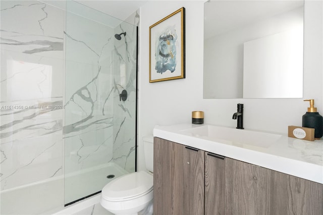 bathroom with a tile shower, vanity, and toilet