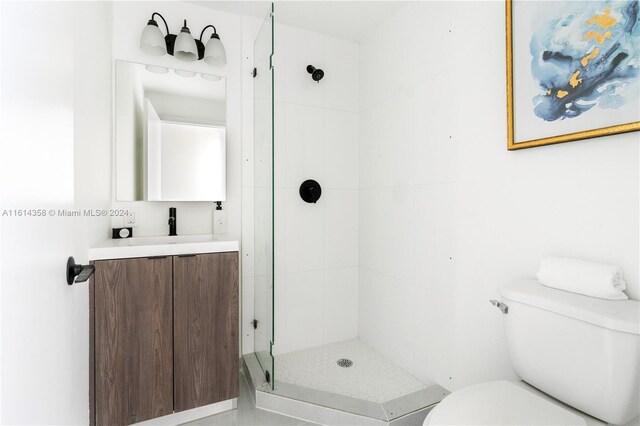 bathroom with vanity, toilet, and tiled shower