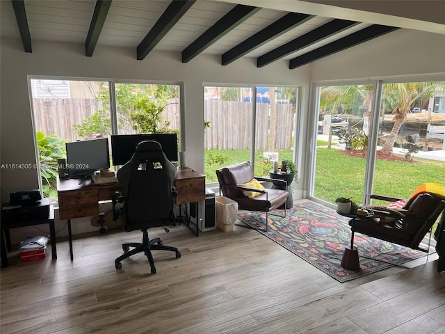 office space featuring a wealth of natural light, wood-type flooring, and lofted ceiling with beams