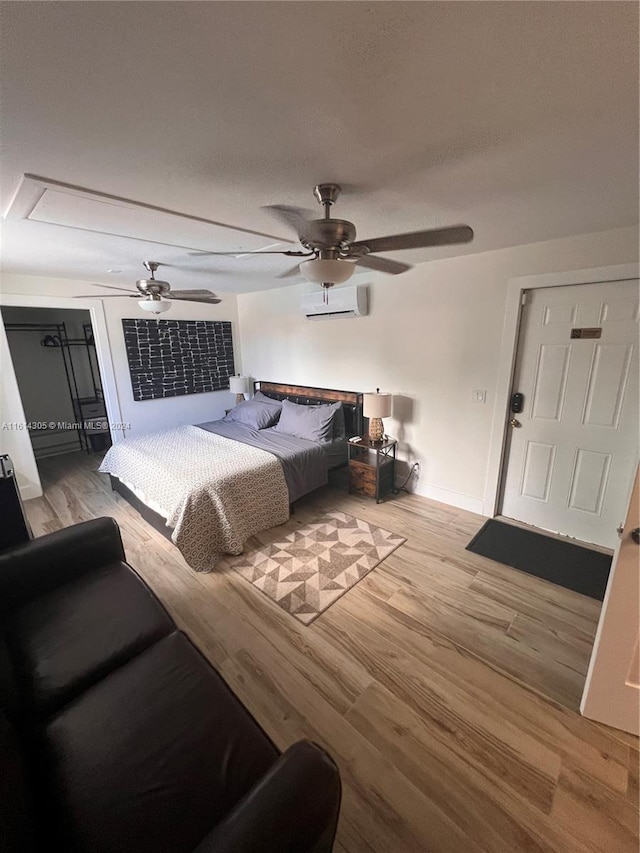 bedroom featuring hardwood / wood-style flooring, ceiling fan, and a wall mounted air conditioner