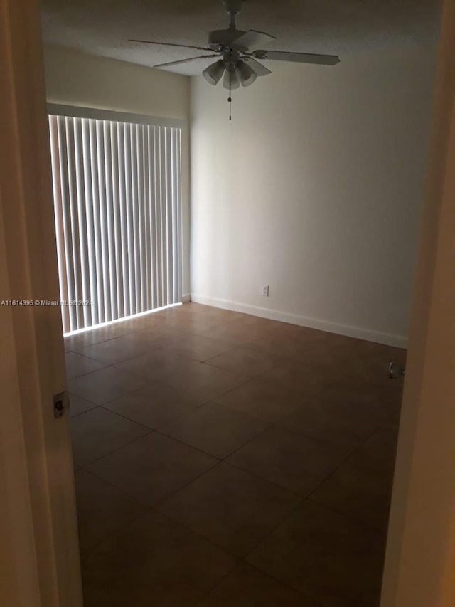 spare room featuring ceiling fan and dark tile patterned floors