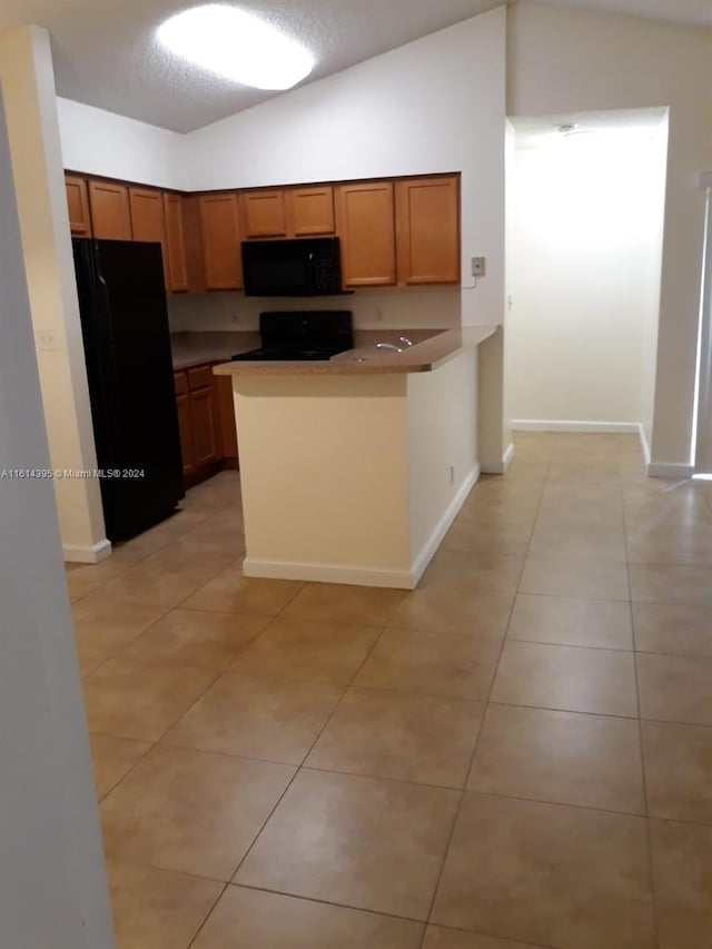 kitchen featuring a textured ceiling, black appliances, lofted ceiling, kitchen peninsula, and light tile patterned floors