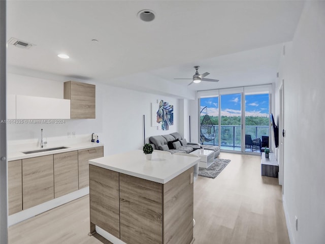 kitchen with light hardwood / wood-style floors, sink, ceiling fan, a wall of windows, and a center island