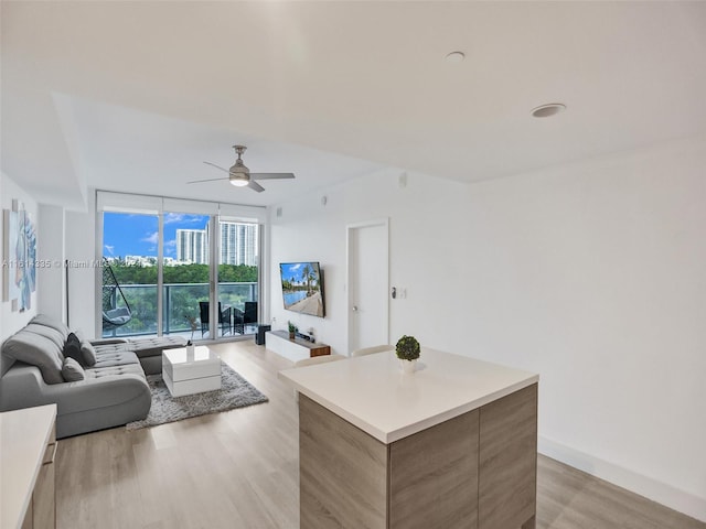 kitchen featuring expansive windows, light hardwood / wood-style flooring, ceiling fan, and a center island