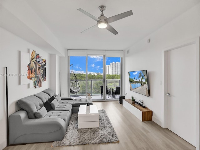 living room featuring ceiling fan, a wall of windows, and light hardwood / wood-style floors