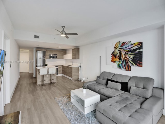 living room featuring sink, ceiling fan, and light hardwood / wood-style flooring