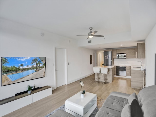 living room featuring light hardwood / wood-style flooring, sink, and ceiling fan