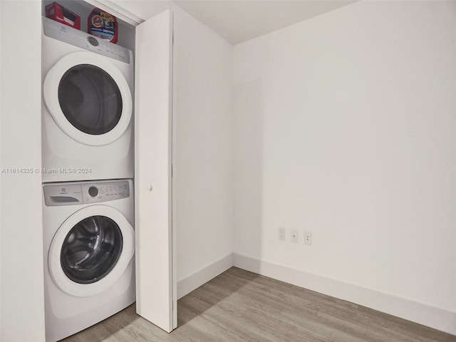 clothes washing area featuring stacked washer / drying machine and light hardwood / wood-style flooring