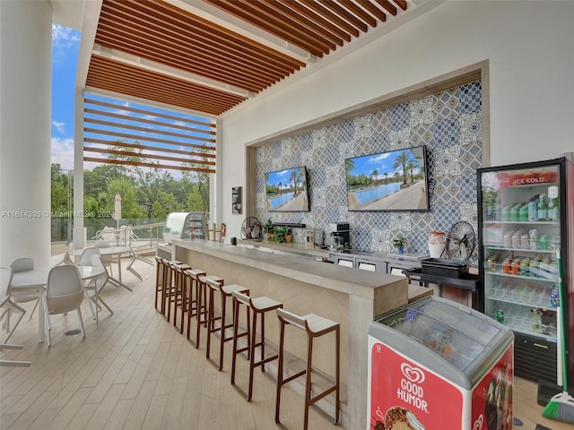 kitchen featuring a kitchen breakfast bar, decorative backsplash, kitchen peninsula, and light hardwood / wood-style floors